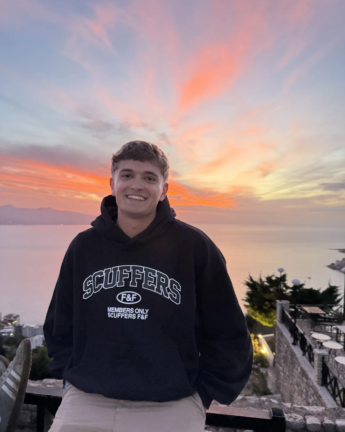 Unax Aller sonriendo al atardecer, con el mar y un cielo naranja de fondo